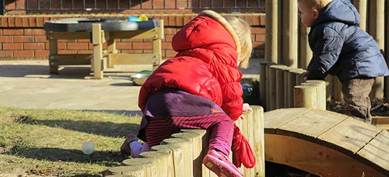 Children climbing and crawling on logs in a playground