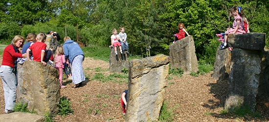 a group of children climbing on rocks with teachers nearby