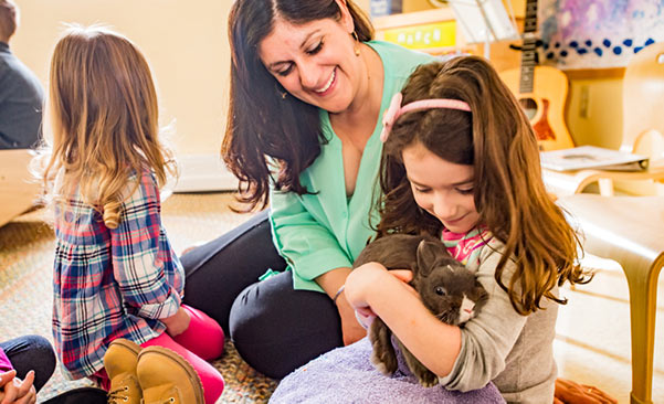 A nursery teacher with two children one of them holding a bunny