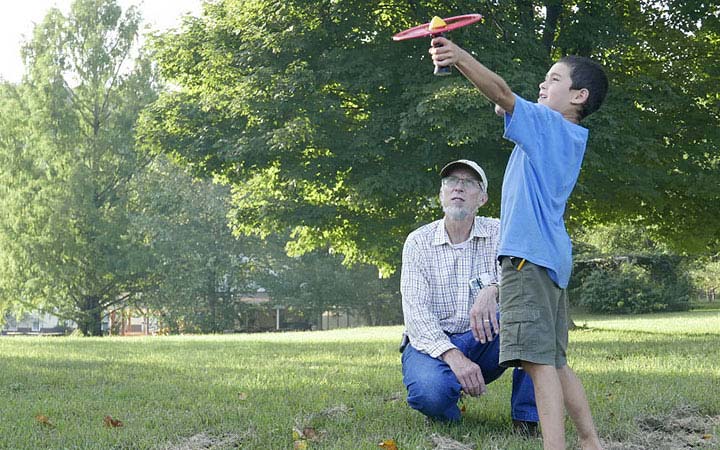 Boy and grandfather outside with a toy helicopter