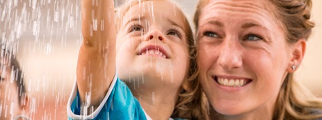 Teacher and child smiling and looking up into the rain