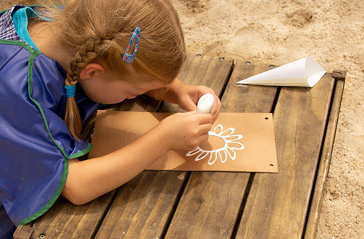 Child tracing sketched lines with glue