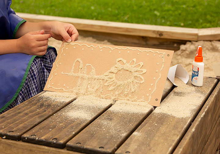 Child shakes surplus sand off sand art painting