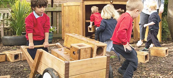 Boy with wheelbarrow transporting wooden blocks