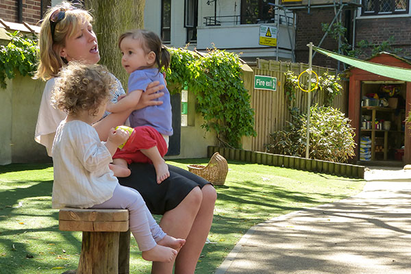 Two children and teacher on bench, singing, talking