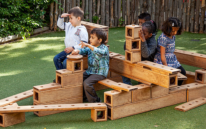 Group of young children pretending to sail on a structure, using imagination during outdoor play.