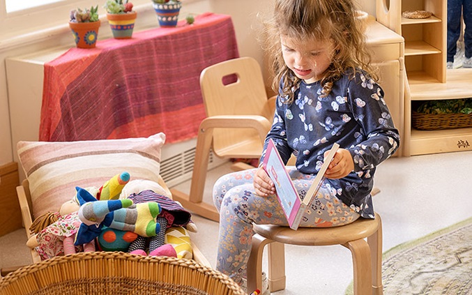 Child on a stool reading a book