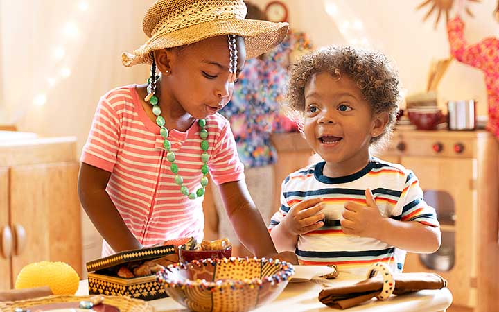 Two preschool aged children playing with loose parts in the role play corner