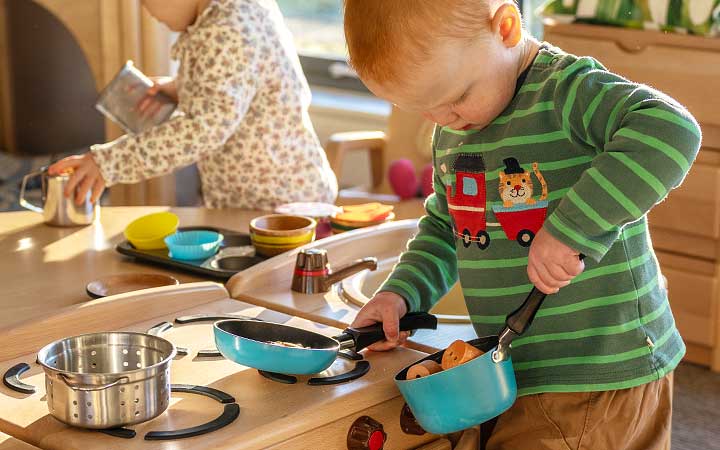 A boy transfering materials in the the role play corner