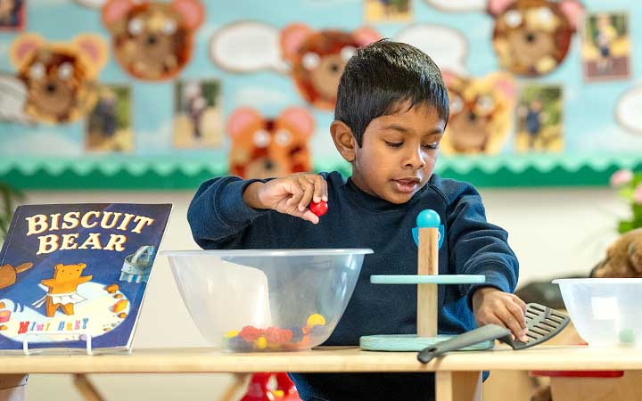 A boy counting and measuring materials in the role play area
