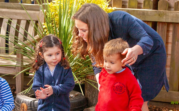 teacher bending down to speak to children