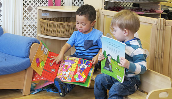 two toddler boys reading books together