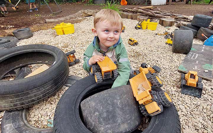 child with yellow truck in play area
