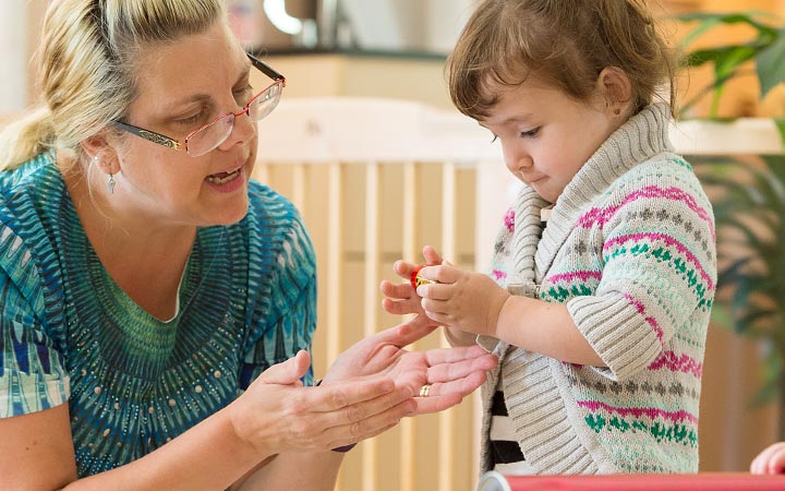 Child interacting with teachers hands
