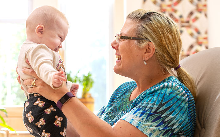 A teacher talking and laughing with an infant on her lap