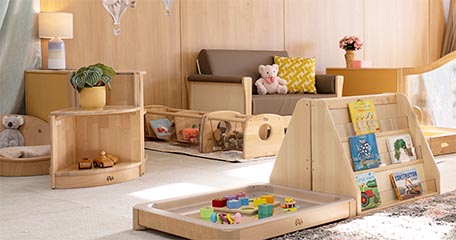A baby room settup with a floor tray for loose parts, and a sofa, shelves, and book display