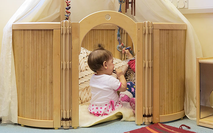 An infant sitting in a cosy space and chewing on a toy