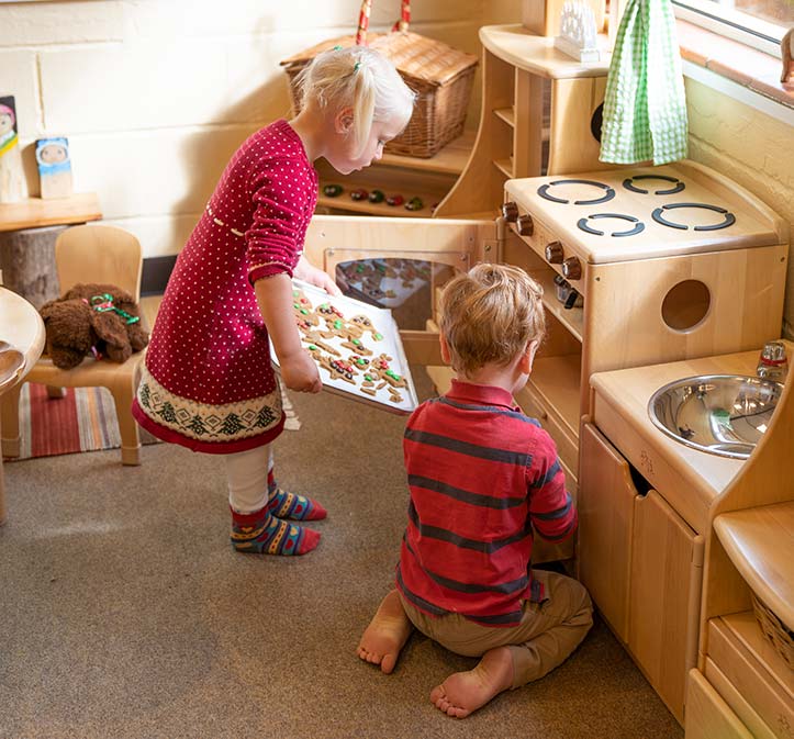 Two children baking with a play kitchen
