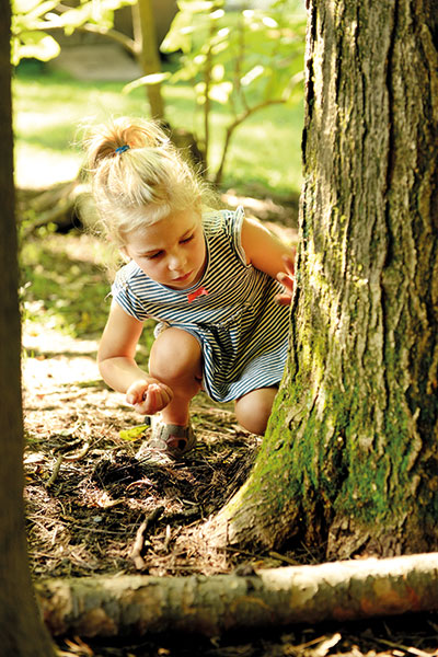 young girl exploring dirt and roots of a tree in nature