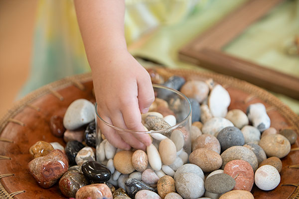 child touching polished stones and pebbles