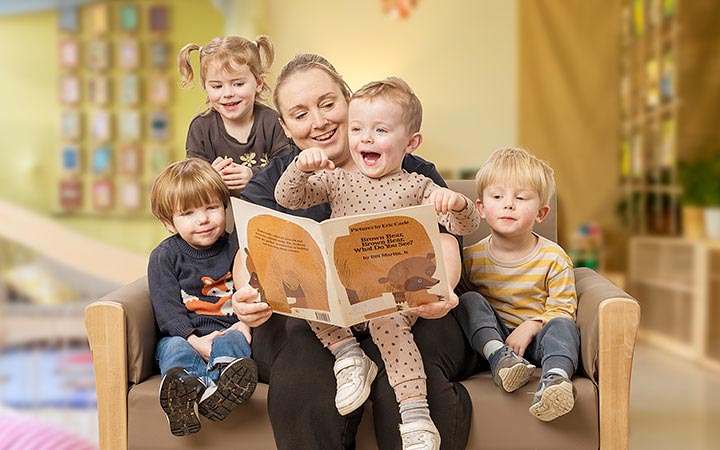 Teacher reading a book with four toddlers