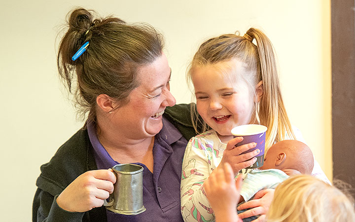 Teacher and preschool girl holding cups and lauging