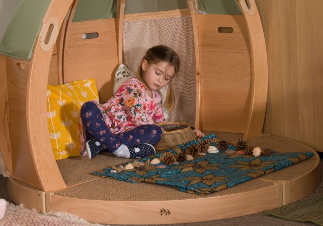 A child plays alone in a wooden self-regulation space