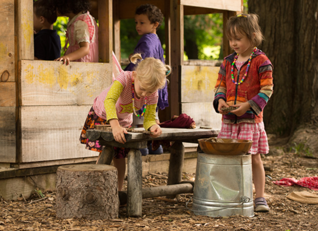 children doing dramatic play in and around a playhouse