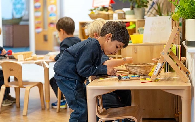 Child playing  at a classroom table with a hammering game.