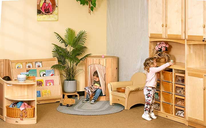 A baby exploring oatmeal at a table with a teacher helping her.