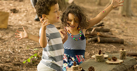 Two children playing outdoors with natural loose parts