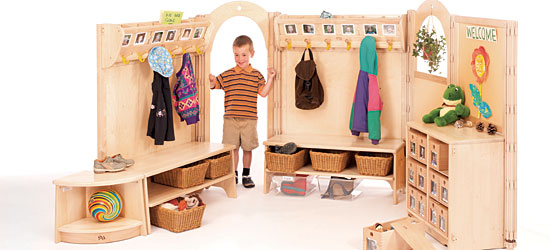A boy in a welcome area with coat hooks, cubbies and benches