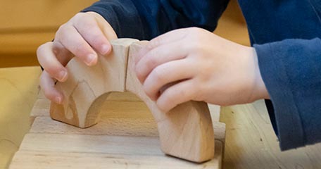 Toddler playing with small wooden blocks