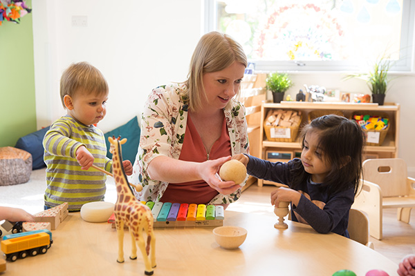 two children handling manipulatives a t a table with teacher