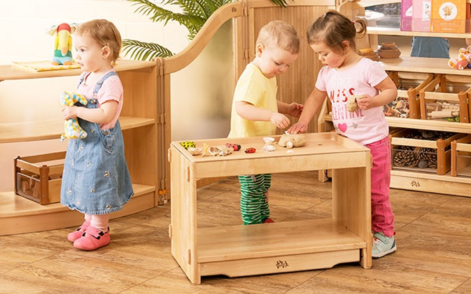 three two-year-olds playing with activity top shelf in display room