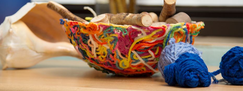 A finished yarn bowl with some balls of yarn in front
