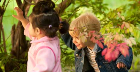 A boy and girl playing in the bushes
