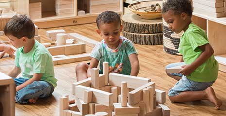 Three nursery aged boys building with unit blocks