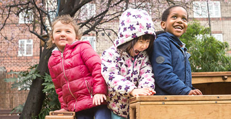 Three laughing children playing with Outlast blocks