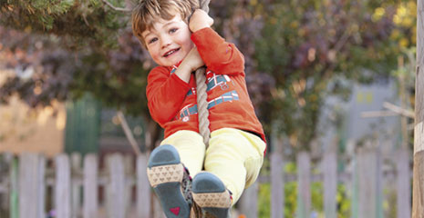 A boy with red sweater on a rope swing