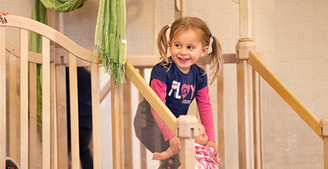 Five year old girl playing on Nursery gym