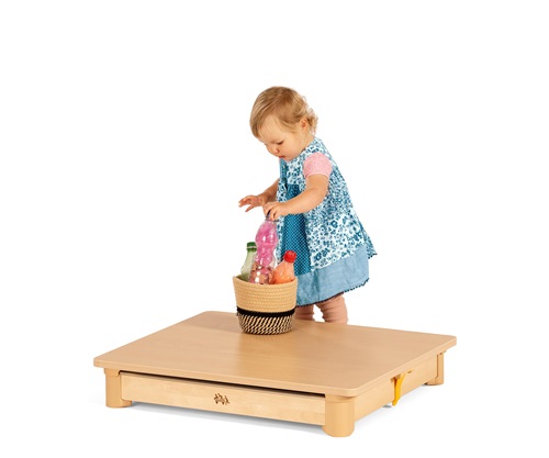 A toddler girl in a blue dress playing with sensory bottles on an Activity floor tray-table