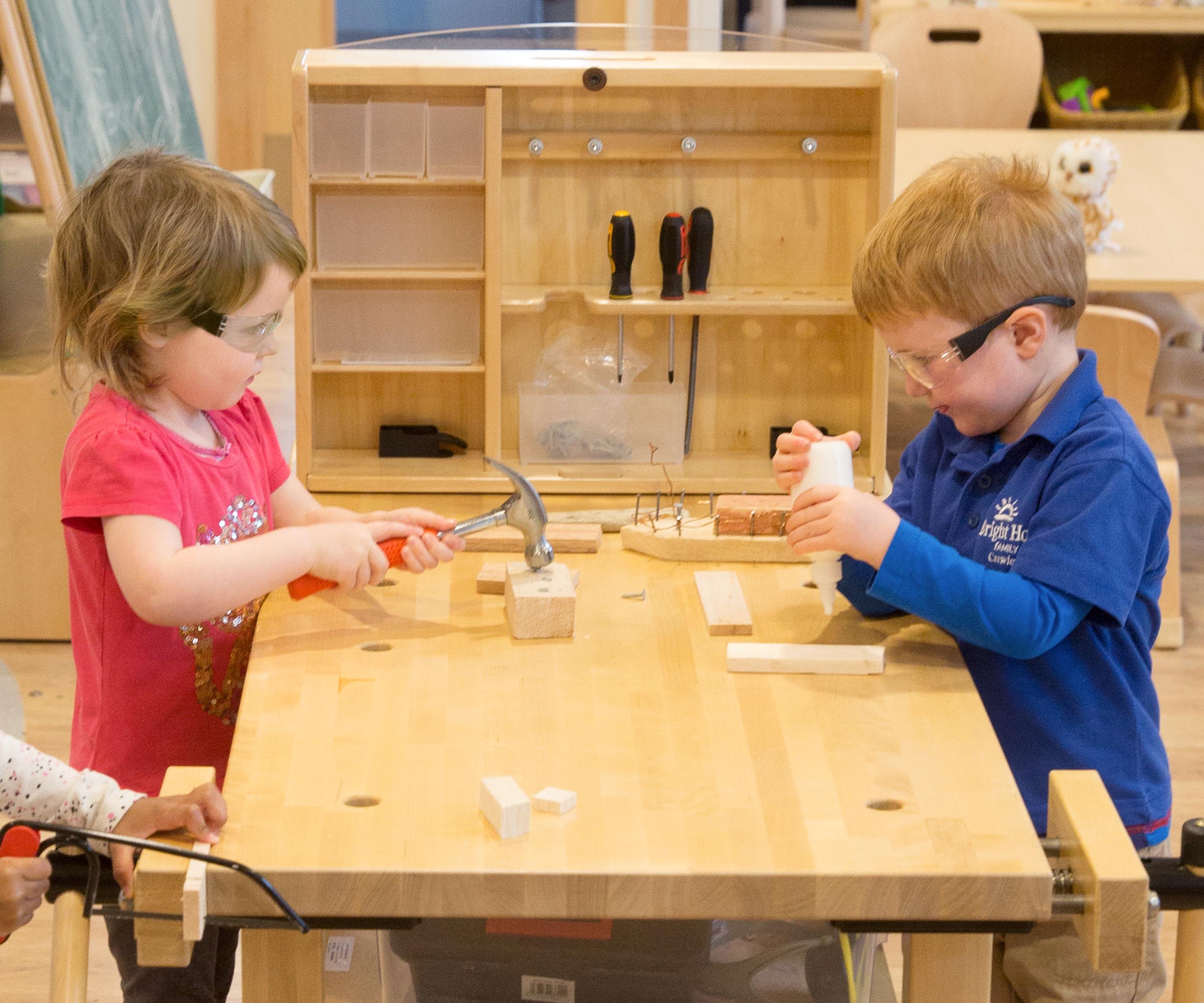   A boy and a girl using childsized tools at a workbench
