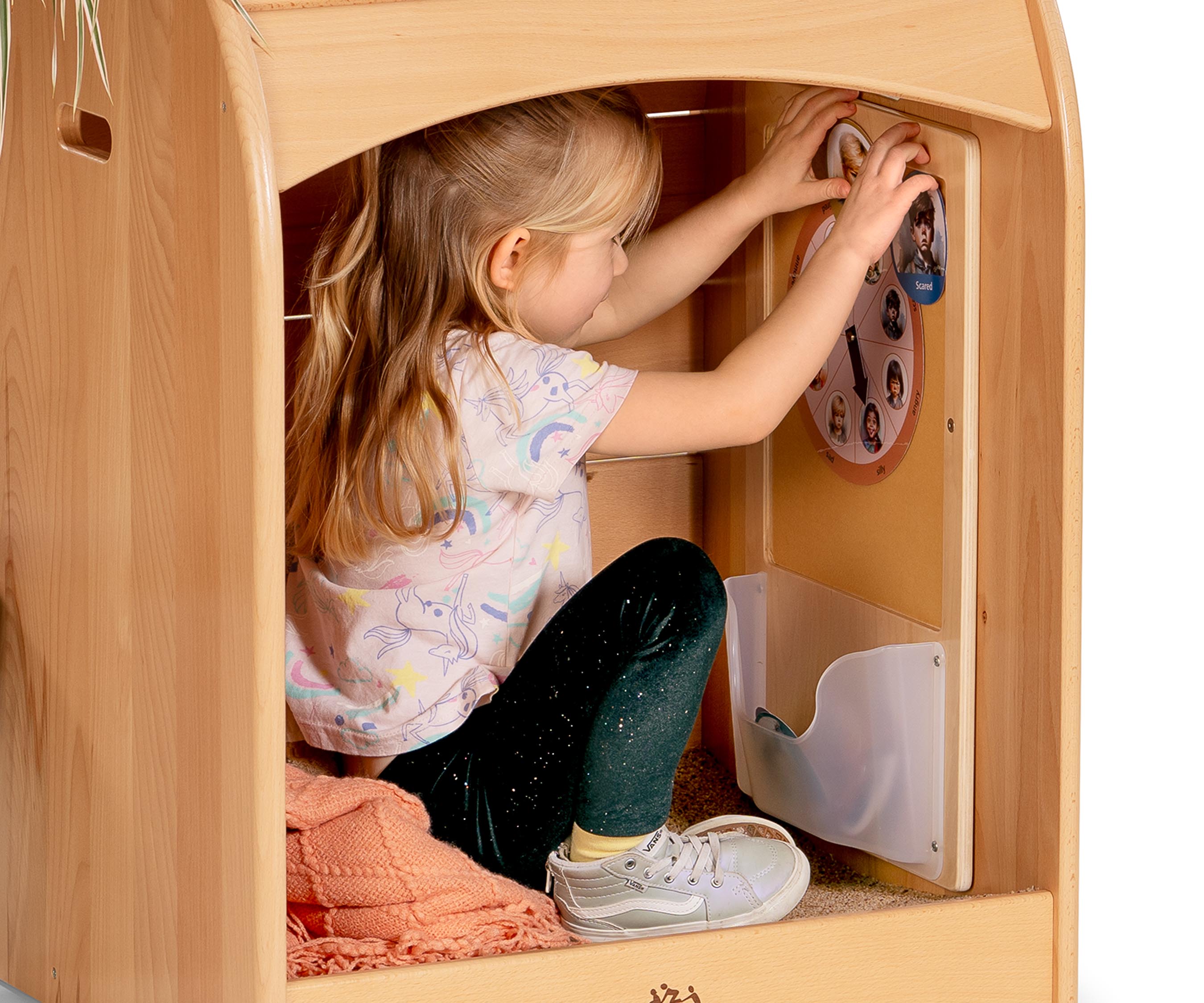 A preschool age girl wearing a pinkish unicorn shirt and placing emotion cards onto the Felt Board in a Nest Nook calm corner