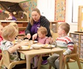children sitting in solid wood nursery chair and eating meal