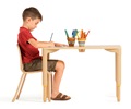 Reception-aged boy seated in a Woodcrest chairs doing mark-making at table