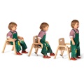 Toddler wearing green overalls sitting in mealtime chair with tray and then standing up
