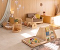 Baby room set up with natural wood furniture, including a Nursery sofa and a sensory floor tray