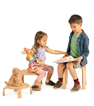 A child sitting on a stacking stool uses a second stool as a table