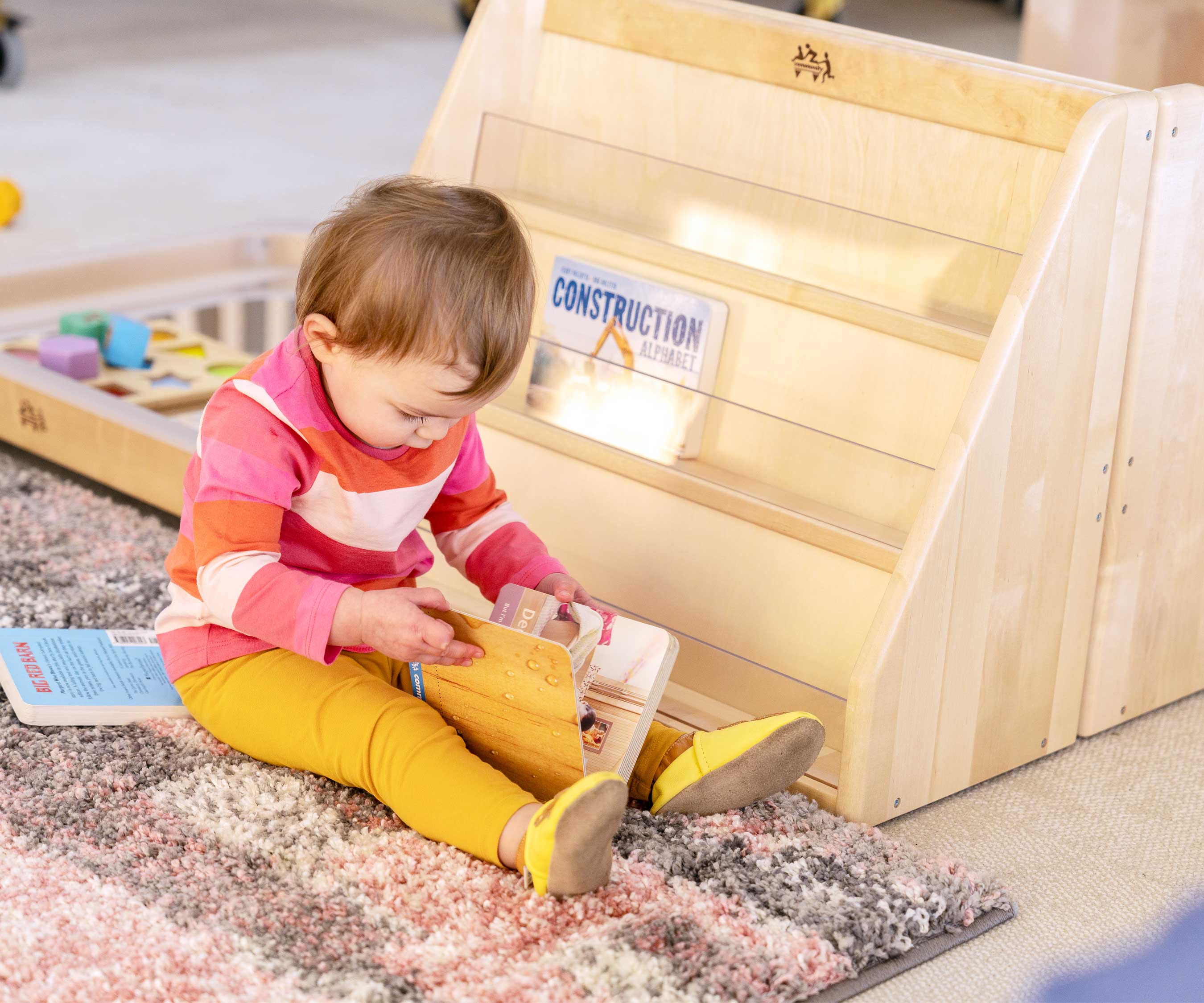 girl by toddler bookshelf